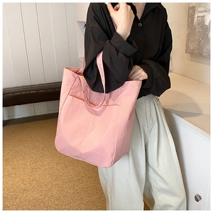 Pink waterproof nylon tote bag with large front pocket and minimalist shoulder strap style