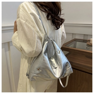 Silver metallic hobo bag with butterfly charms shown worn over the shoulder