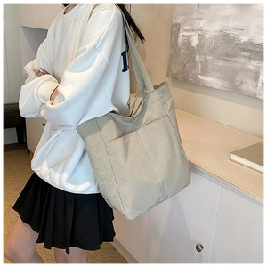 Detail of grey lightweight nylon tote bag showing dual front pockets and textured fabric