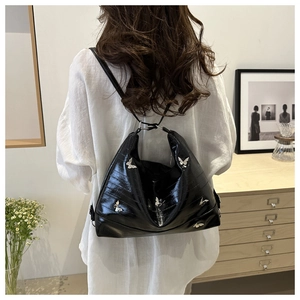 Black glossy patent leather shoulder bag with silver butterfly charms detail macro
