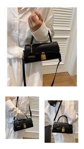 Detail of black leather handbag with gold padlock hardware and Fashion charm tag