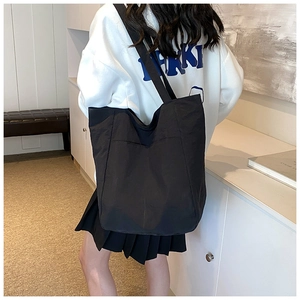 Detailed shoulder view of a black minimalist tote bag with large front pocket and texture