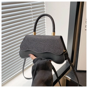 Dettaglio della borsa a tracolla con paillettes nere, hardware dorato e patta ondulata