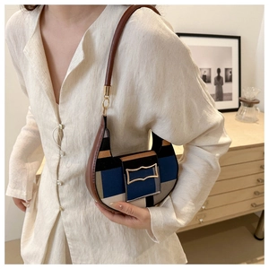 Detail of a color-block half-moon shoulder bag featuring a unique gold metal buckle