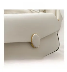 Gros plan d'un sac en cuir blanc avec boucle dorée ovale et finitions de bords noirs