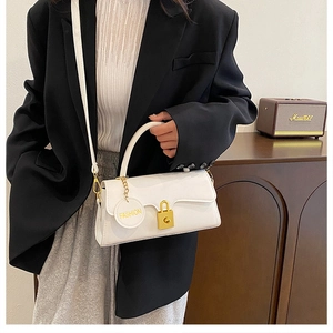 Detail of white leather handbag featuring gold twist-lock and fashion hangtag charm