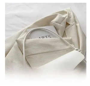 Détail du sac à main minimaliste en cuir crème avec anse nouée et boucle métallique