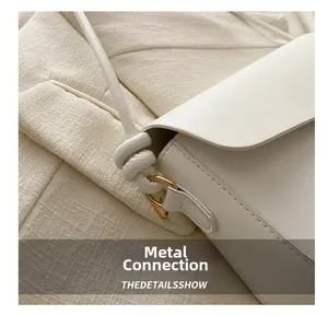 Détail du sac blanc en cuir avec anneau en métal doré et bandoulière à nœud unique