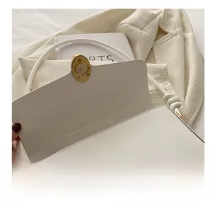 Détail de la boucle en métal doré sur le sac à bandoulière en cuir blanc élégant