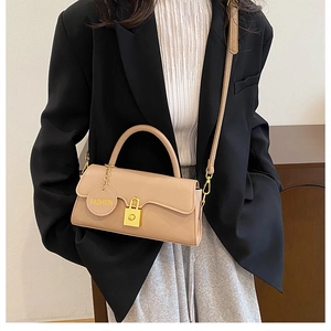 Close-up of beige leather shoulder bag with golden buckle and fashion charm detail