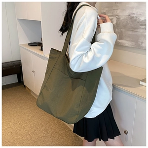Close-up of olive green nylon tote bag with front pocket and wide shoulder strap detail