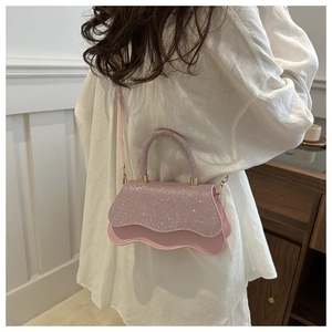 Détail du sac à bandoulière rose à paillettes avec bord festonné et finitions dorées