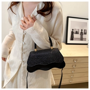 Detailed view of black sequin evening bag featuring a wave base and gold hardware hooks