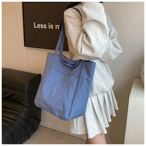 Side view of large light blue nylon tote bag with front pocket shown on a model