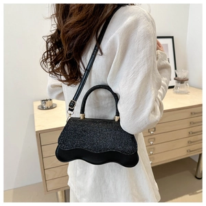 Detailed side view of a black sequined handbag with wave design and gold hardware
