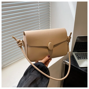 Détail du sac beige avec boucle ovale et bandoulière aux finitions nouées