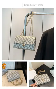 Detail view of white crossbody bag with black floral pattern and gold chain strap