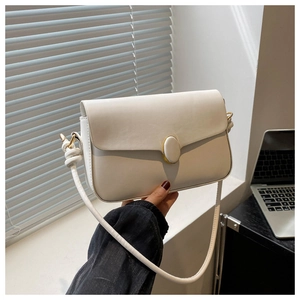 Détail du sac à bandoulière ivoire avec fermoir ovale et design de bandoulière nouée