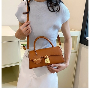 Detailed shot of brown faux leather underarm bag with gold lock and fashion charm