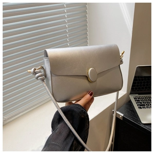 Détail d'un sac à main argenté métallisé avec boucle dorée et bandoulière nouée élégante