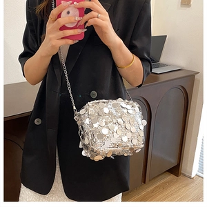 Detail of shimmering silver sequin crossbody bag with metallic chain on black blazer