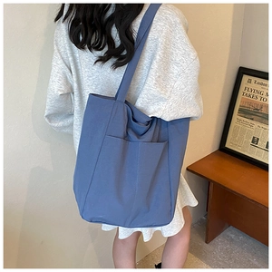 Blue large capacity oxford tote bag shown in a real-life commuting shoulder scenario