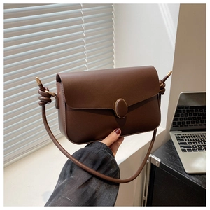 Détail du sac à bandoulière en cuir marron foncé avec nœud de sangle et boucle vintage