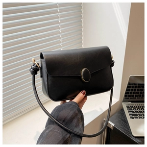 Détail du sac à bandoulière en cuir noir avec serrure dorée et bandoulière à nœuds