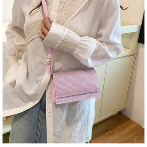 Kleine rosa Glitzertasche mit verstellbarem Riemen getragen auf weißem Spitzentop
