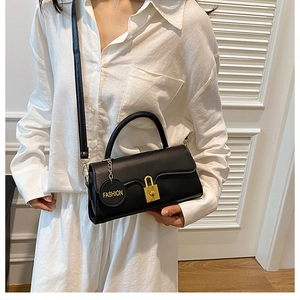 Detail of black leather handbag with gold clasp and Fashion charm on the shoulder strap
