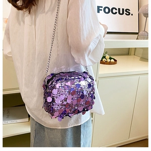 Close-up of a purple sequined shoulder bag with a silver chain strap worn by a model