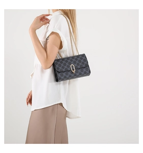 Detail view of dark grey patterned shoulder bag with gold chain and metal clasp