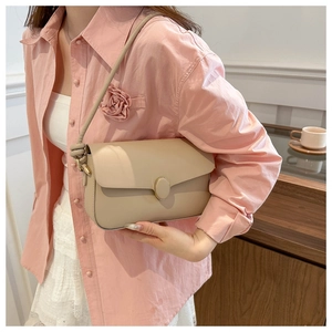 Détail du sac à bandoulière en cuir beige clair avec boucle dorée et fine lanière