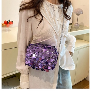 Detail of purple sequin crossbody bag with silver chain strap shown in a lifestyle setting