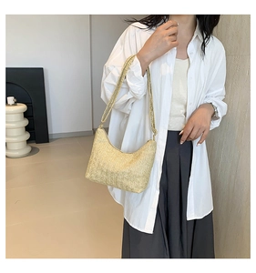 Détail d'un sac hobo en paille tressée à motif chevrons porté par un mannequin