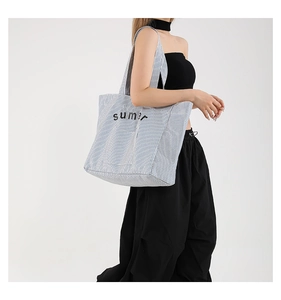 Detail of blue and white striped canvas tote bag with black summer text and cotton texture