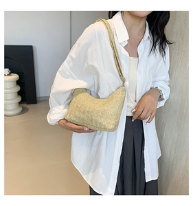 Détail du sac bandoulière en paille tressée en forme de croissant avec texture beige