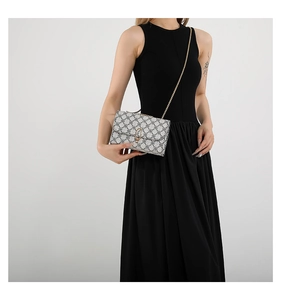 Close-up of geometric pattern crossbody bag with gold chain and U-lock on black dress