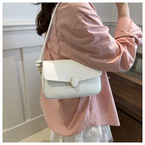 Détail latéral d'un sac bandoulière blanc minimaliste avec nœud décoratif sur la sangle