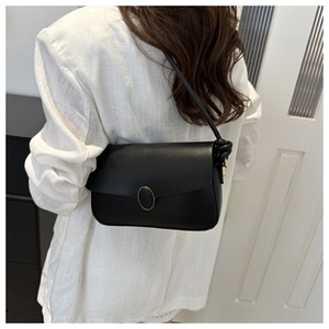 Détail d'un sac à bandoulière noir avec boucle dorée et design de bandoulière à nœuds