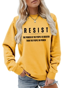 Detailansicht eines senfgelben Rundhals-Sweatshirts mit markantem Resist-Schriftzug