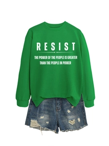 Flachbild eines grünen Crewneck-Sweatshirts mit RESIST-Aufdruck und zerrissenen Denim-Shorts