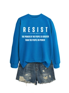Nahaufnahme von königsblauem Sweatshirt mit RESIST-Aufdruck und zerrissenen Jeans-Shorts