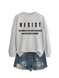 Detail eines grauen Sweatshirts mit RESIST-Aufdruck und zerrissenen Denim-Shorts