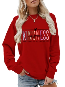 Détail du sweat rouge avec le slogan Kindness is free et des poignets côtelés