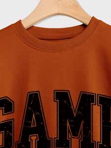 Détail du col ras du cou et de l'imprimé vintage sur le sweat-shirt orange