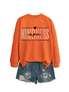Mise à plat du sweat orange imprimé Kindness is Free et du short en jean déchiré