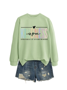 Détail du sweat vert clair Kindness is Free assorti à un short en jean déchiré