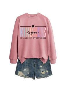 Détail du texte artistique Kindness Is Free sur un sweat-shirt rose en coton doux