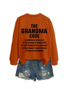 Détail du sweat orange avec imprimé The Grandma Code et mini short en jean déchiré tendance